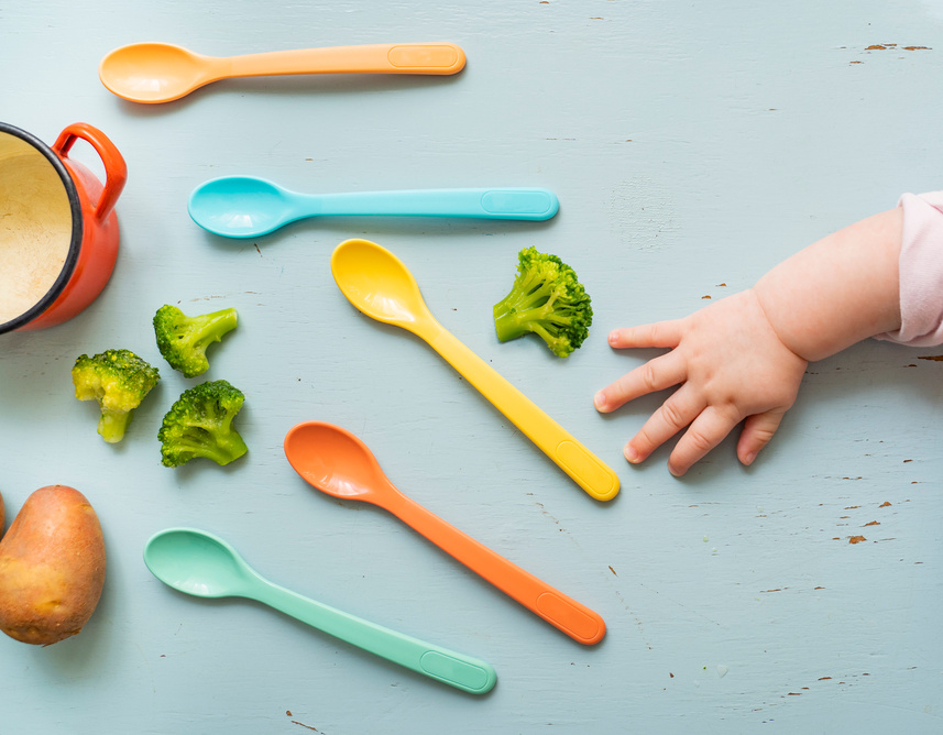 Cute baby hand reaching for spoon, Baby food concept